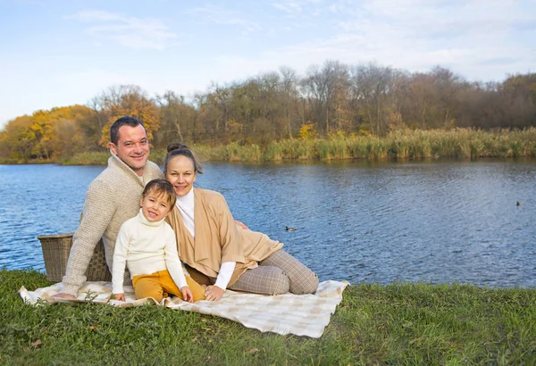 Young family resting on the lake shore — Stock Photo, Image