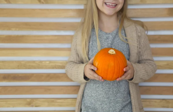 Gelukkig klein meisje met herfst pompoen door de houten muur blauw — Stockfoto