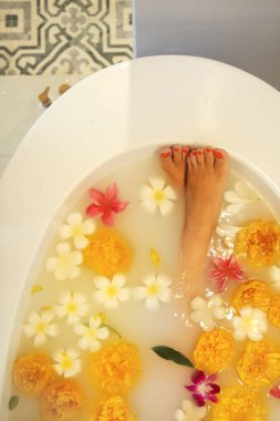 Süt ve çiçeklerle banyoda genç kadın 