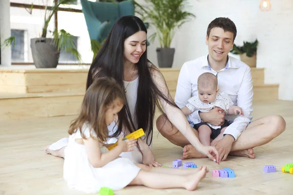 Família feliz brincando com blocos coloridos em casa — Fotografia de Stock