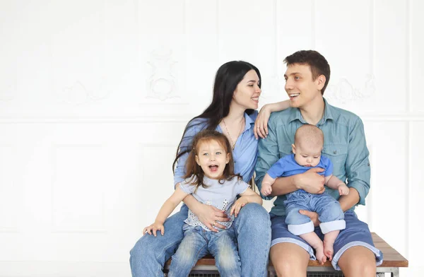 Glückliche junge Eltern mit ihren entzückenden kleinen Kindern zu Hause — Stockfoto