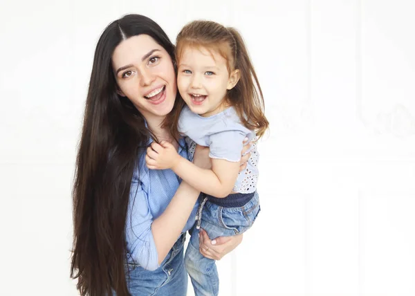 Glückliche junge helle Mutter umarmt ihre kleine Tochter — Stockfoto