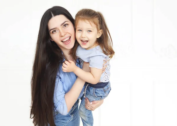 Feliz jovem brilhante mãe abraçando sua filhinha — Fotografia de Stock