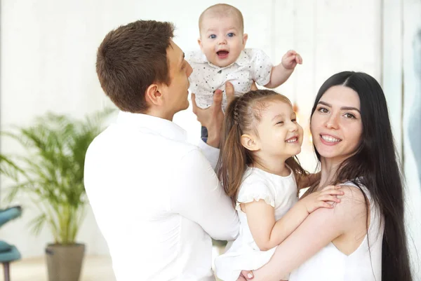 Felices padres jóvenes con sus adorables niños pequeños en casa —  Fotos de Stock