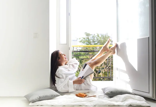 Молодая красивая женщина читает журнал на балконе — стоковое фото