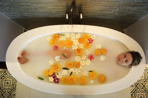 Молодая женщина в ванной с молоком и цветами — стоковое фото