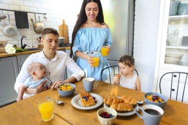 Aile mutfakta kahvaltı yapıyor. 