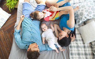 Mutlu gülümseyen beyaz aile yatakta yatan