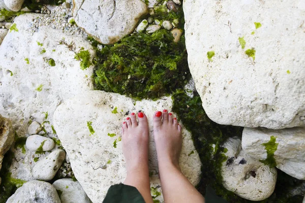 海辺の光の石に赤いペディキュアを持つ女性の足 — ストック写真