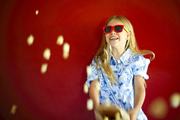 Menina vestindo óculos de sol e comendo pipocas — Fotografia de Stock