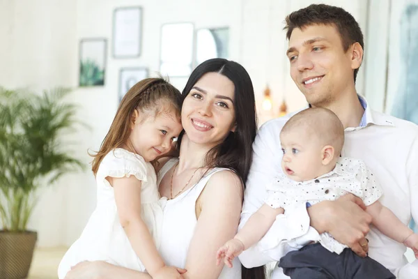 Felices padres jóvenes con sus adorables niños pequeños en casa —  Fotos de Stock