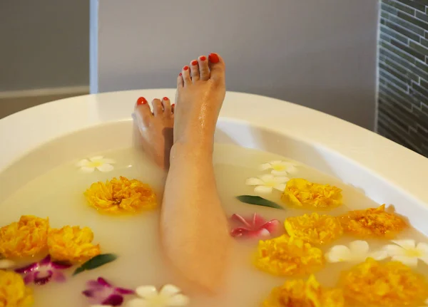 Fiatal nő fürdőben tejjel és virágok — Stock Fotó
