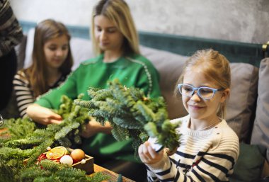 Köknar dallarından noel çelengi yapan aile, noel balosu