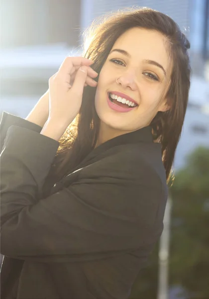 Young woman in jacket standing on balcony with city background a — Stock Photo, Image