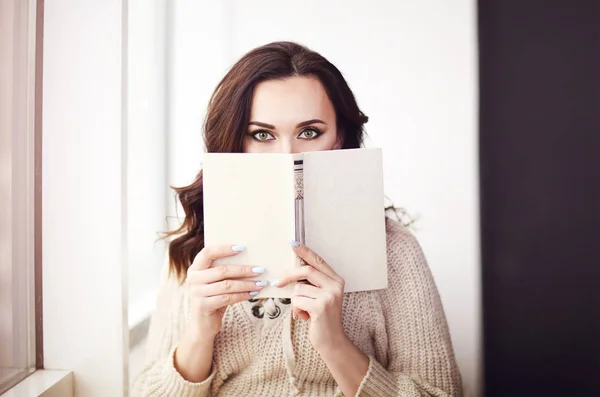 ニットセーター読書を着ている若い美しいブルネットの女性 — ストック写真