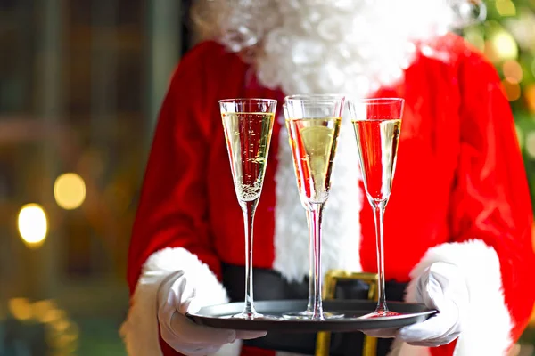 Papai Noel segurando copos de champanhe na bandeja — Fotografia de Stock