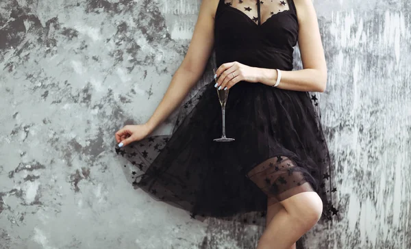Smiling woman in black dress with a glass of champagne. — Stock Photo, Image