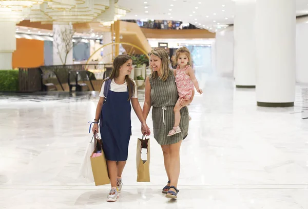 Madre e figlie che camminano con le borse della spesa — Foto Stock