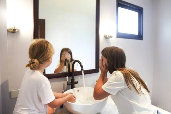 Filles enfants heureux se lavent le visage dans une salle de bain — Photo