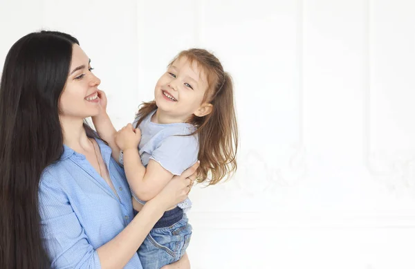 Feliz jovem brilhante mãe abraçando sua filhinha — Fotografia de Stock