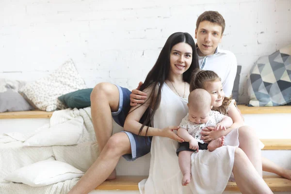 Glada unga föräldrar med sina söta små barn hemma — Stockfoto