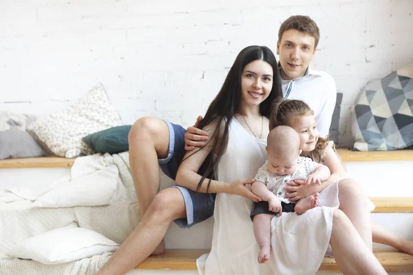 Jovens pais felizes com seus filhos adoráveis em casa — Fotografia de Stock