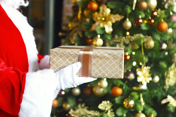 Santa Claus secretly putting gift box by the Christmas tree — Stock Photo, Image