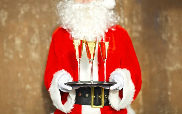 Papai Noel segurando copos de champanhe na bandeja — Fotografia de Stock