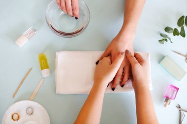 Modern salonda kadın müşterinin tırnaklarını ojeleyen isimsiz bir manikürcü.