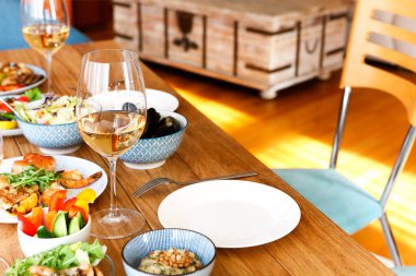 Yüksek açılı ahşap masa çeşitli ev yapımı tabaklar ve evde konforlu oturma odasında şarap ile servis edilir.