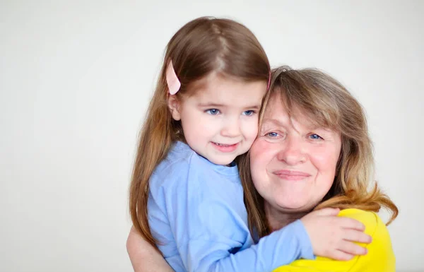 Smiling Middle Aged Grandmother Little Granddaughter Hugging Looking Camera While — Stock Photo, Image