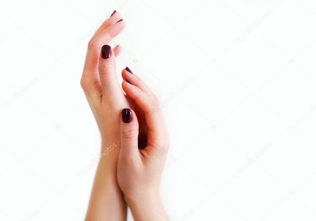 Top view of crop anonymous female with painted dark nails keeping hands over light background