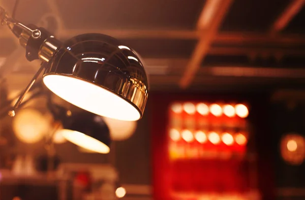 背景がぼやけて照明室に輝くミラーメタルランプシェードと現代のランプの低角度クローズアップ — ストック写真