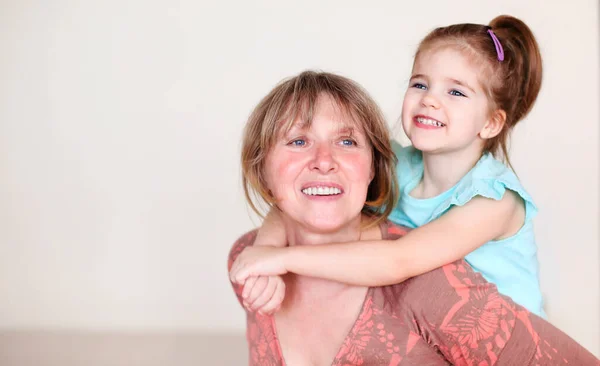 Smiling Middle Aged Grandmother Little Granddaughter Hugging Looking Camera While — Stock Photo, Image