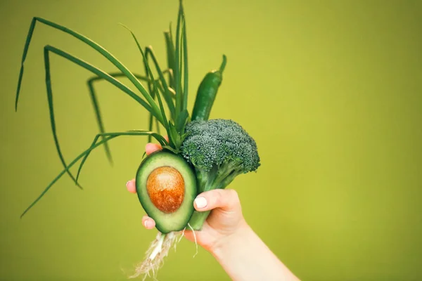 緑の背景を背景に食事中に健康的な新鮮な野菜の束を示す認識できない女性 — ストック写真
