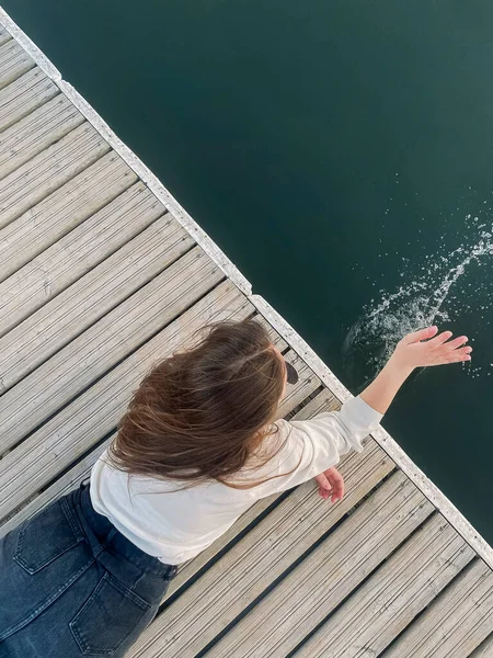 夏日躺在码头上 泼洒清澈湖水的无法辨认的年轻女子的头像 — 图库照片