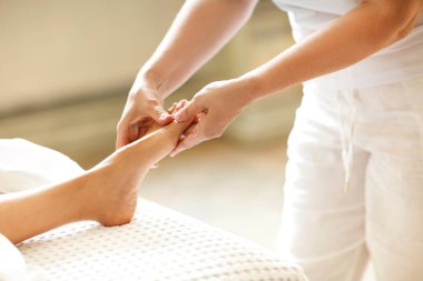 Tanımlanamayan terapist, spa salonunda çalışırken isimsiz müşteriye masaj yapmak için ayak dosyası kullanıyor.