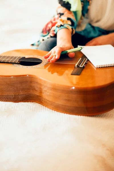 Обрізати Жіночого Музиканта Акустичною Гітарою Ноутбуком Роблячи Нотатки Сидячи Ліжку — стокове фото