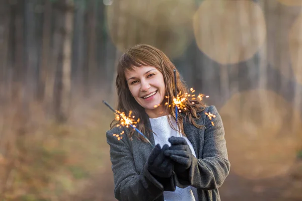 在冬天的森林里 一个笑容可亲 快乐的漂亮女人在灯火通明地享受着 — 图库照片