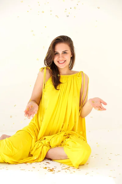 Молода Щаслива Жінка Жовтій Сукні Конфетті Шкіра Сидить Розважається Білому — стокове фото