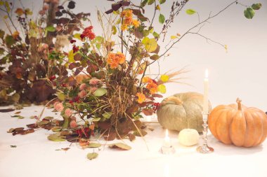 Küçük balkabakları ve yanan mumlar bir demet kuru çiçeğin yanına konur ve Cadılar Bayramı kutlamaları sırasında sisin içinde bırakır.