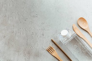 Gri taş yüzeyinde su ve nane yaprağı ile şişenin yanına yerleştirilmiş çevre dostu aletlerin üst görüntüsü