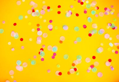 Stüdyoda parti sırasında sarı arkaplana saçılmış çok renkli konfeti manzarası