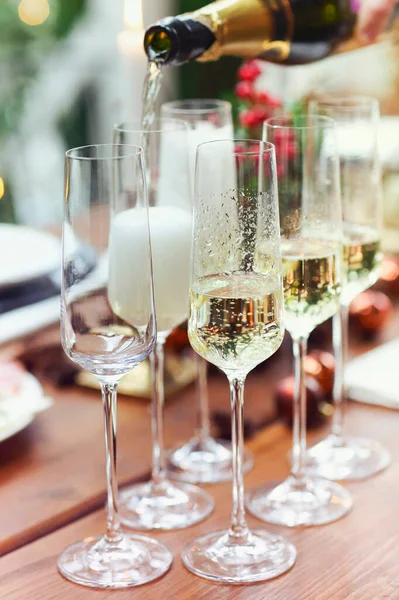クリスマスパーティー中にろうそくを燃やして宴会テーブルの近くに立っている間 認識できない男性がシャンパンでワイングラスを充填自宅で — ストック写真