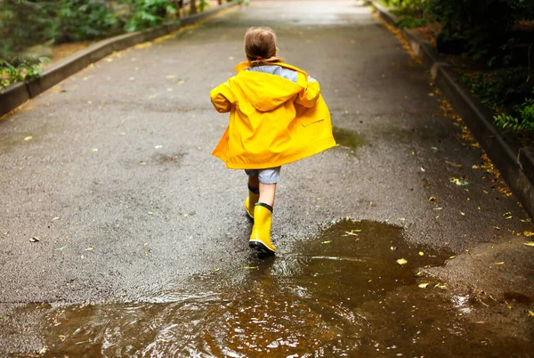 Sarı Çizme Palto Giyen Küçük Kız Yağmurlu Bir Günde Zıplıyor — Stok fotoğraf