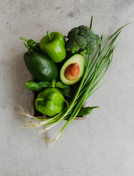 以灰色背景放置于容器内的各种新鲜绿色蔬菜的顶部视图 — 图库照片