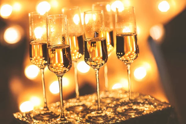 パーティー中の明るい照明の背景に置かれたシャンパンと透明なワイングラス — ストック写真