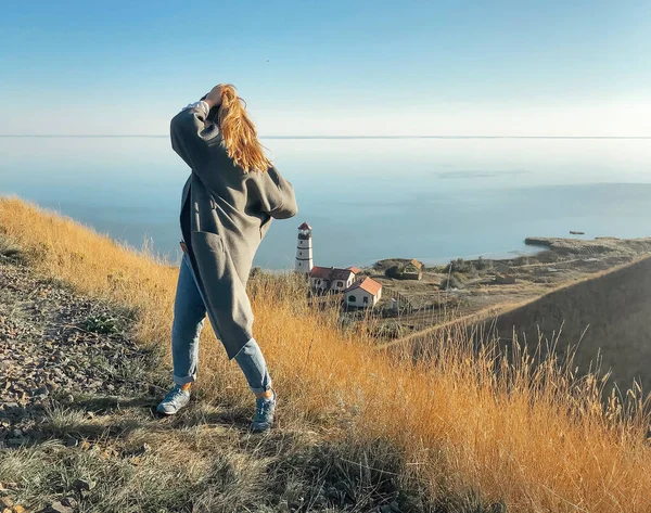 草の丘の上に立つ女性の認識できない景色と夕日と感動的な髪の間に素晴らしい景色を賞賛 — ストック写真