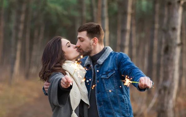 秋の森の中で愛とキスしながら燃える輝きで手を伸ばし暖かい服のハンサムな男と女 — ストック写真