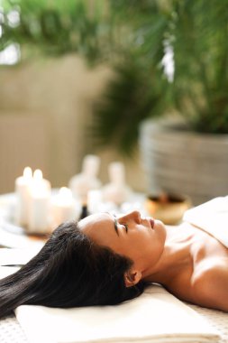 Salondaki kaplıca oturumunda gözleri kapalı, dinlenen etnik kadın müşterinin yan görüntüsü